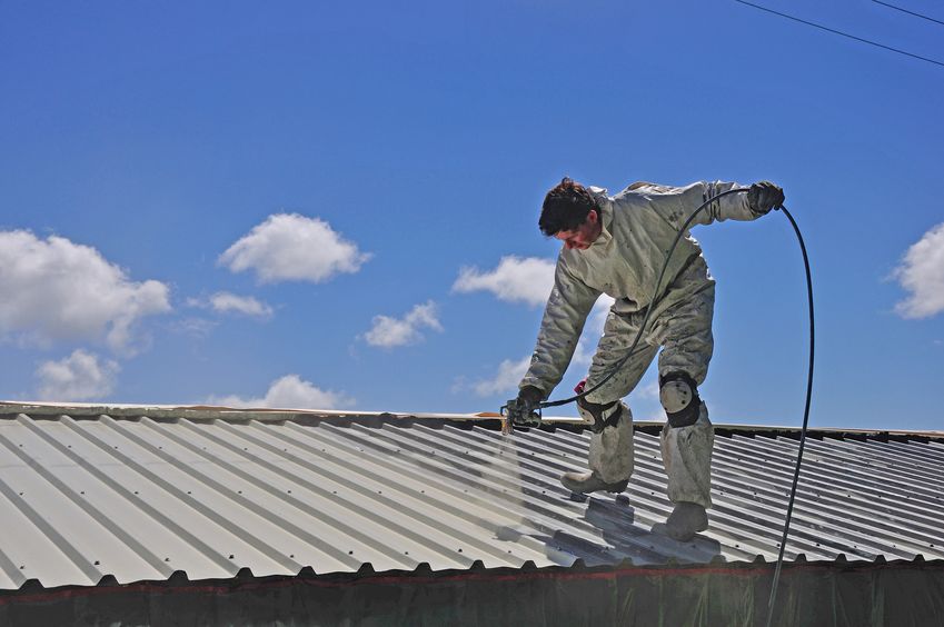 a tradesman uses an airless spray to paint the roof of a building